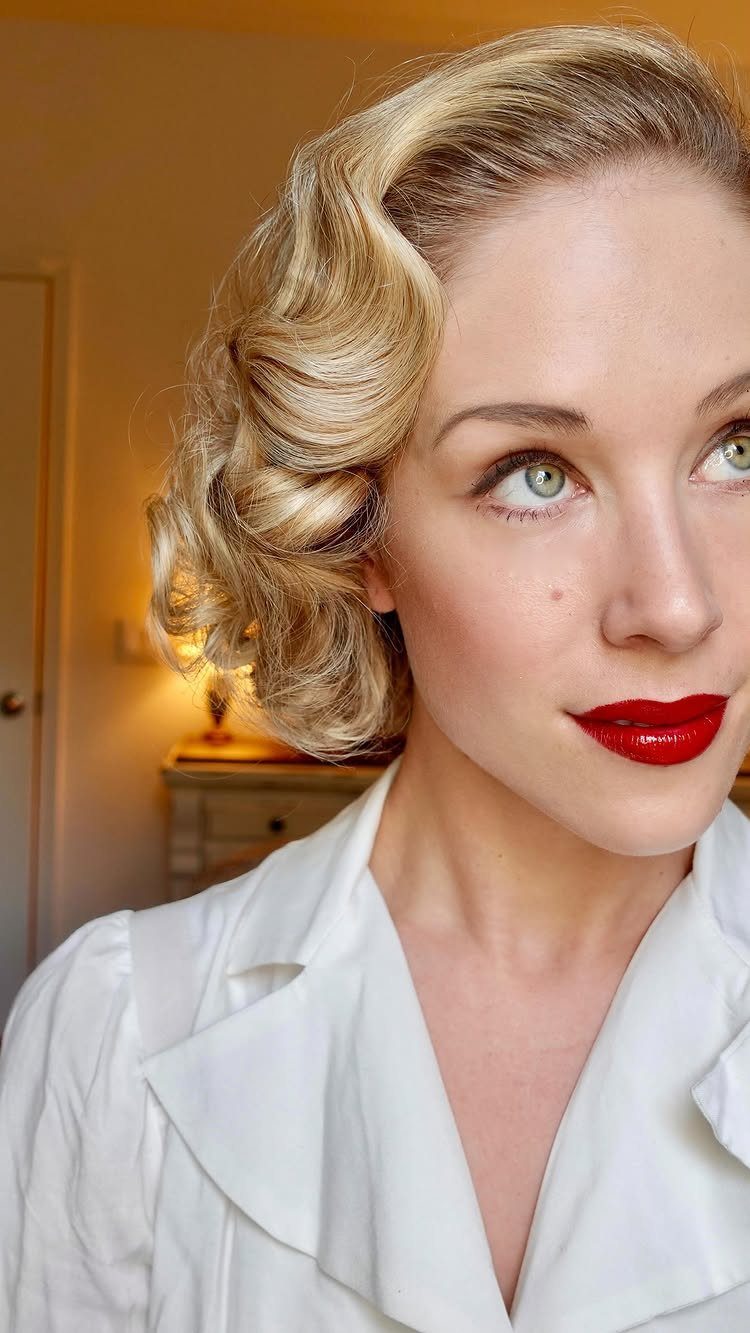 Blonde woman with vintage finger waves and bold red lipstick looking upwards.