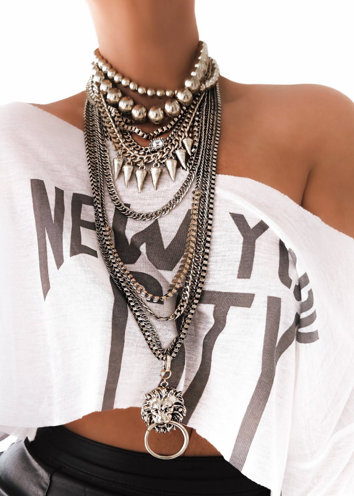 A person wearing a heavy, multi-layered silver statement necklace with spikes and a lion pendant.