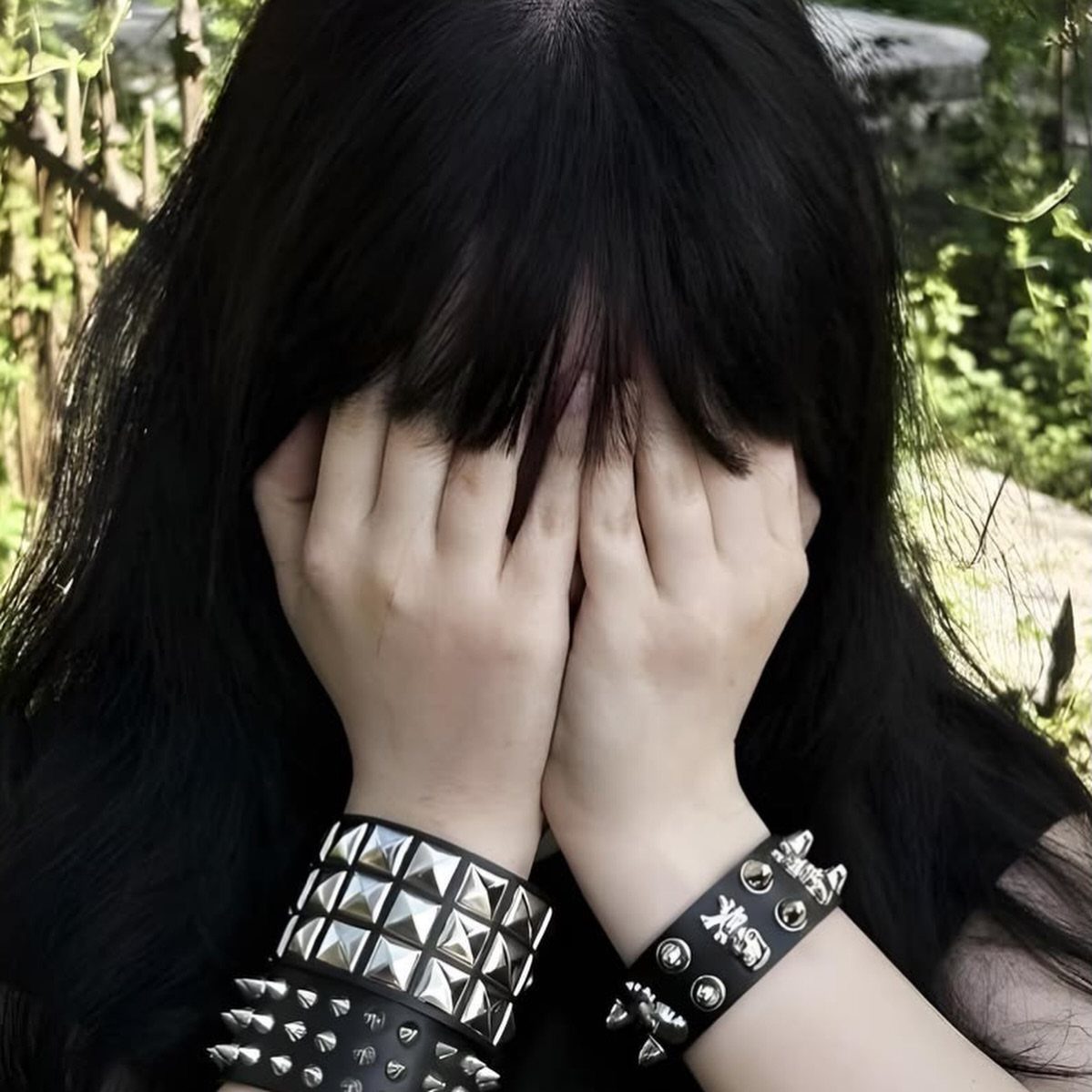 Person with black hair wearing wide black leather wristbands with large silver metal studs.