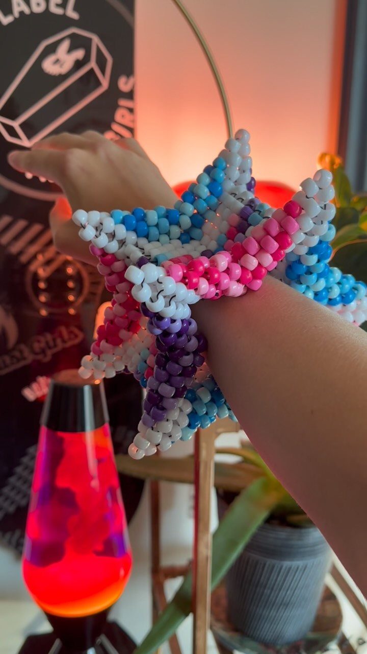 A person's arm adorned with large, colorful beaded Kandi bracelets in blue, pink, and white.