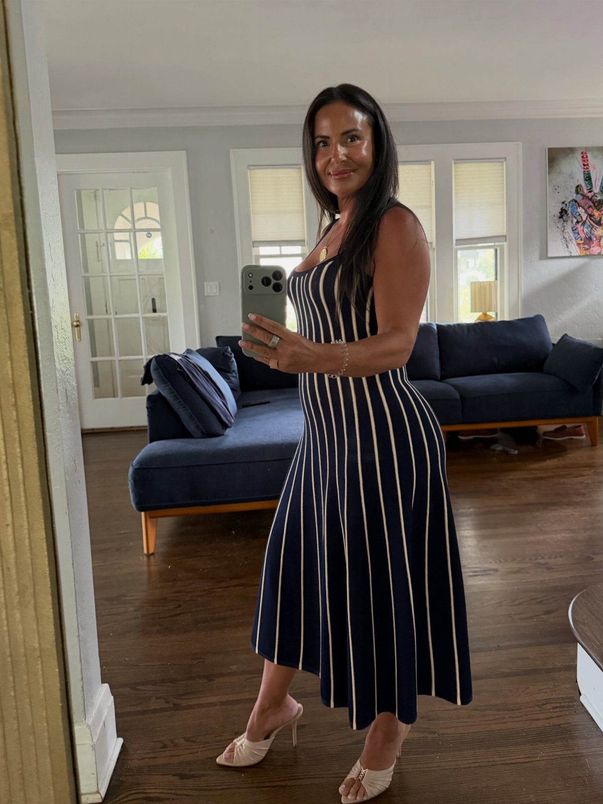 A woman in a navy and white striped midi dress posing for a mirror selfie.