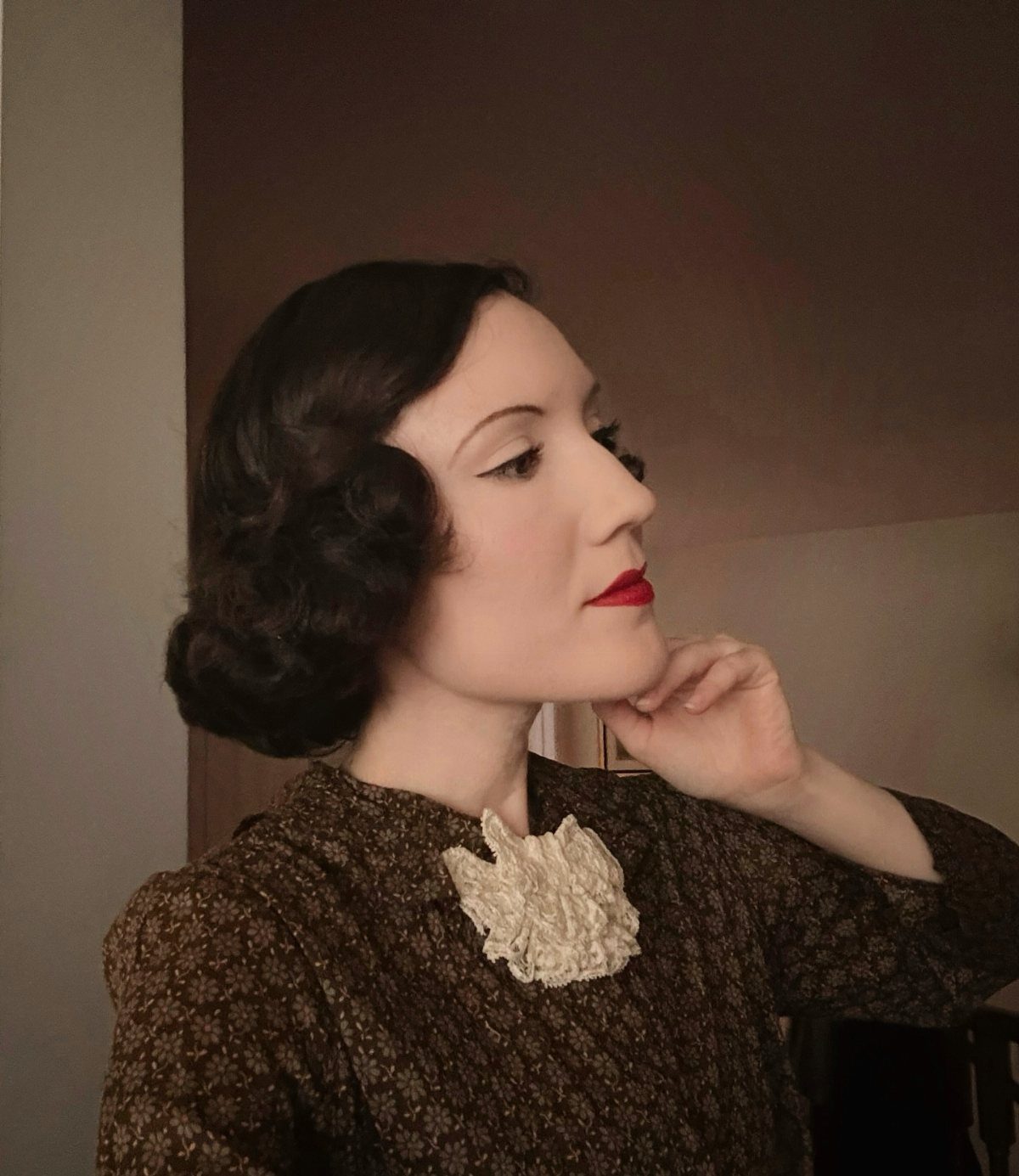 Woman with dark finger wave hair and red lipstick posing in a vintage patterned dress.