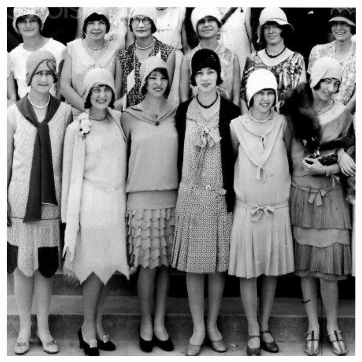 Group of women in 1920s attire wearing various cloche hats and vintage dresses.