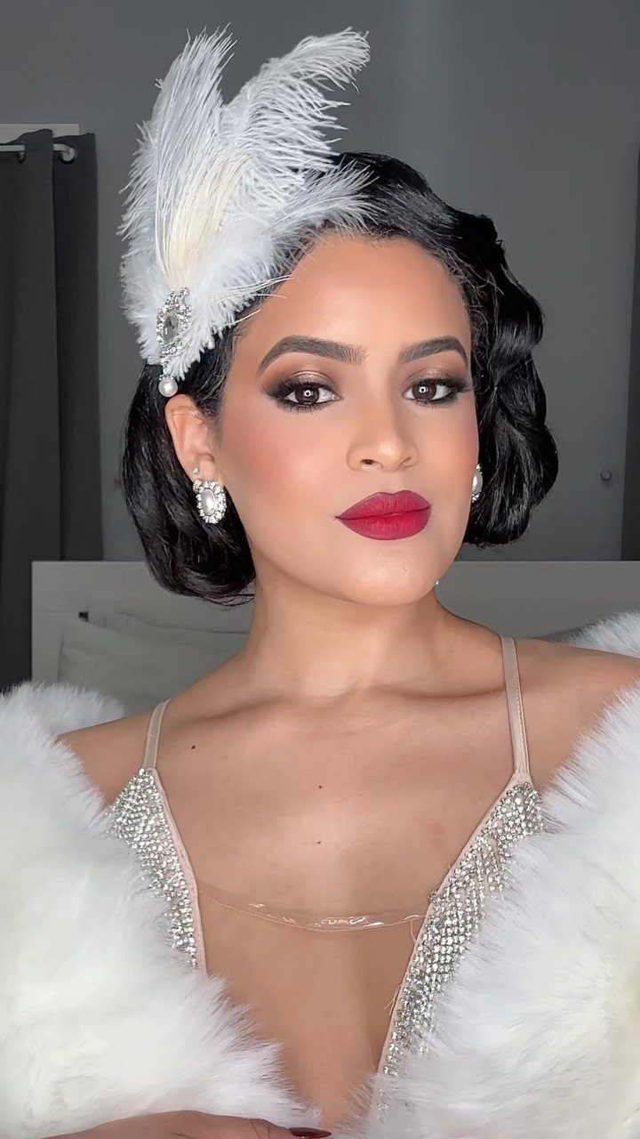 Woman with finger-wave hair wearing a white feather headband and sequined dress.