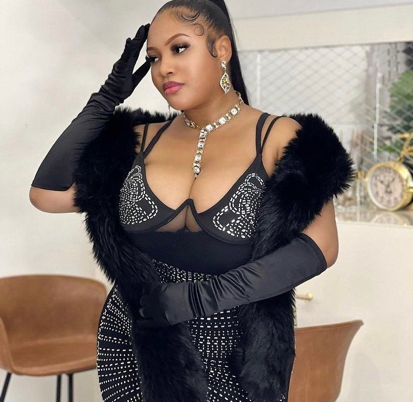Woman in a black sequined dress and fur stole wearing long black satin gloves.