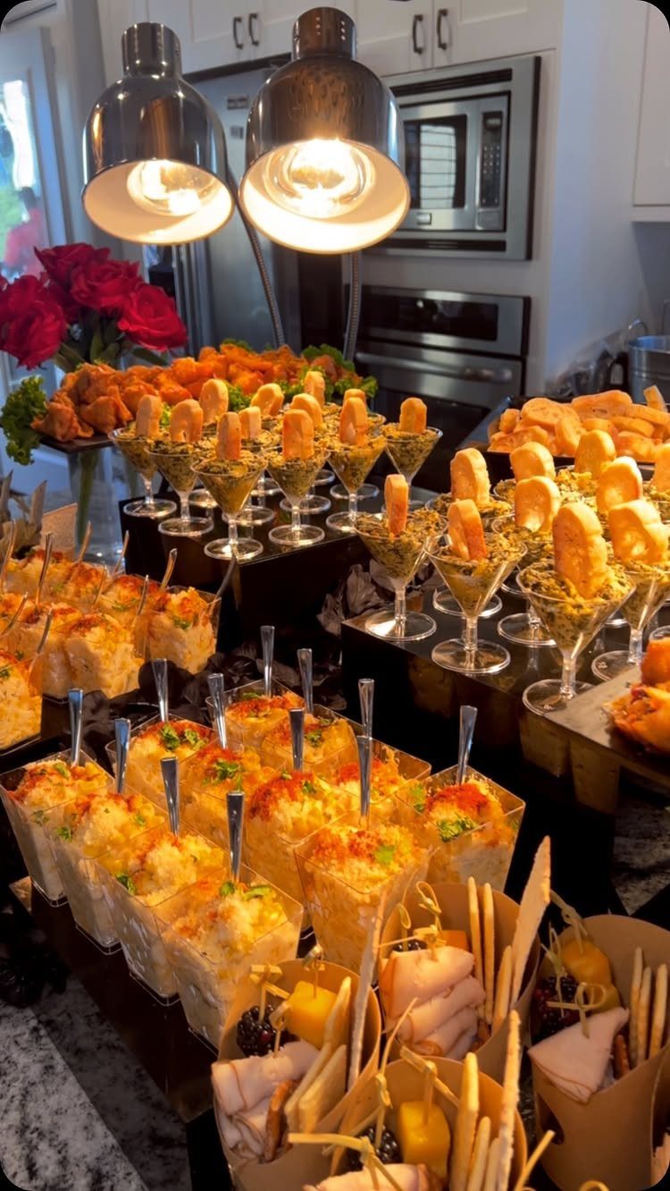 Assorted elegant appetizers and finger foods served in small glasses and paper cones on a buffet table.