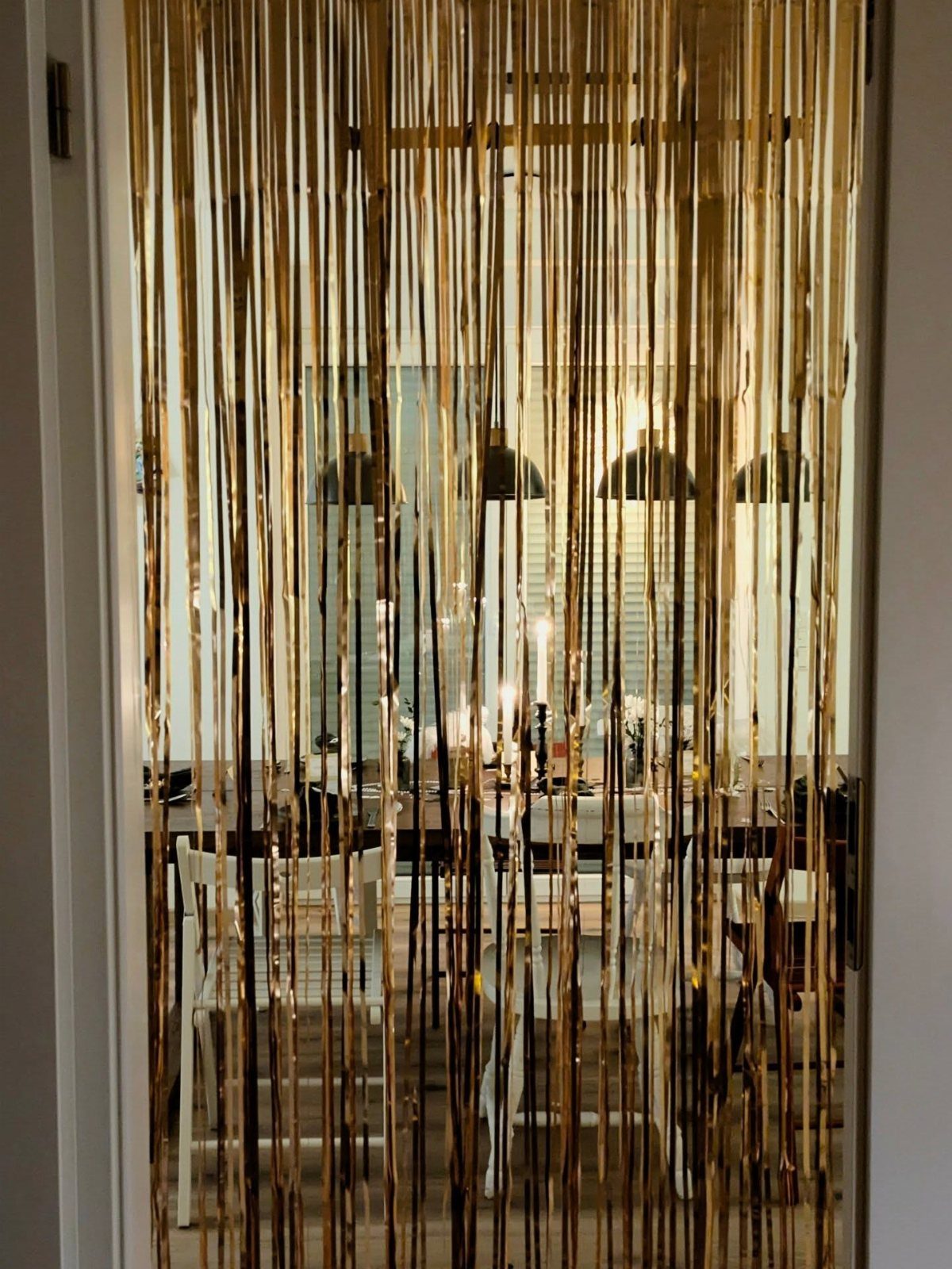 Gold metallic fringe curtain hanging in a doorway overlooking a dining room area.
