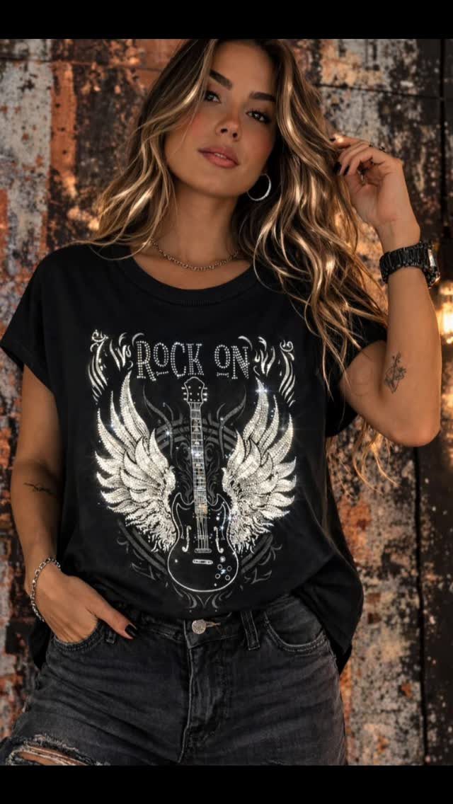 A woman wearing a black winged guitar graphic t-shirt and distressed denim jeans.