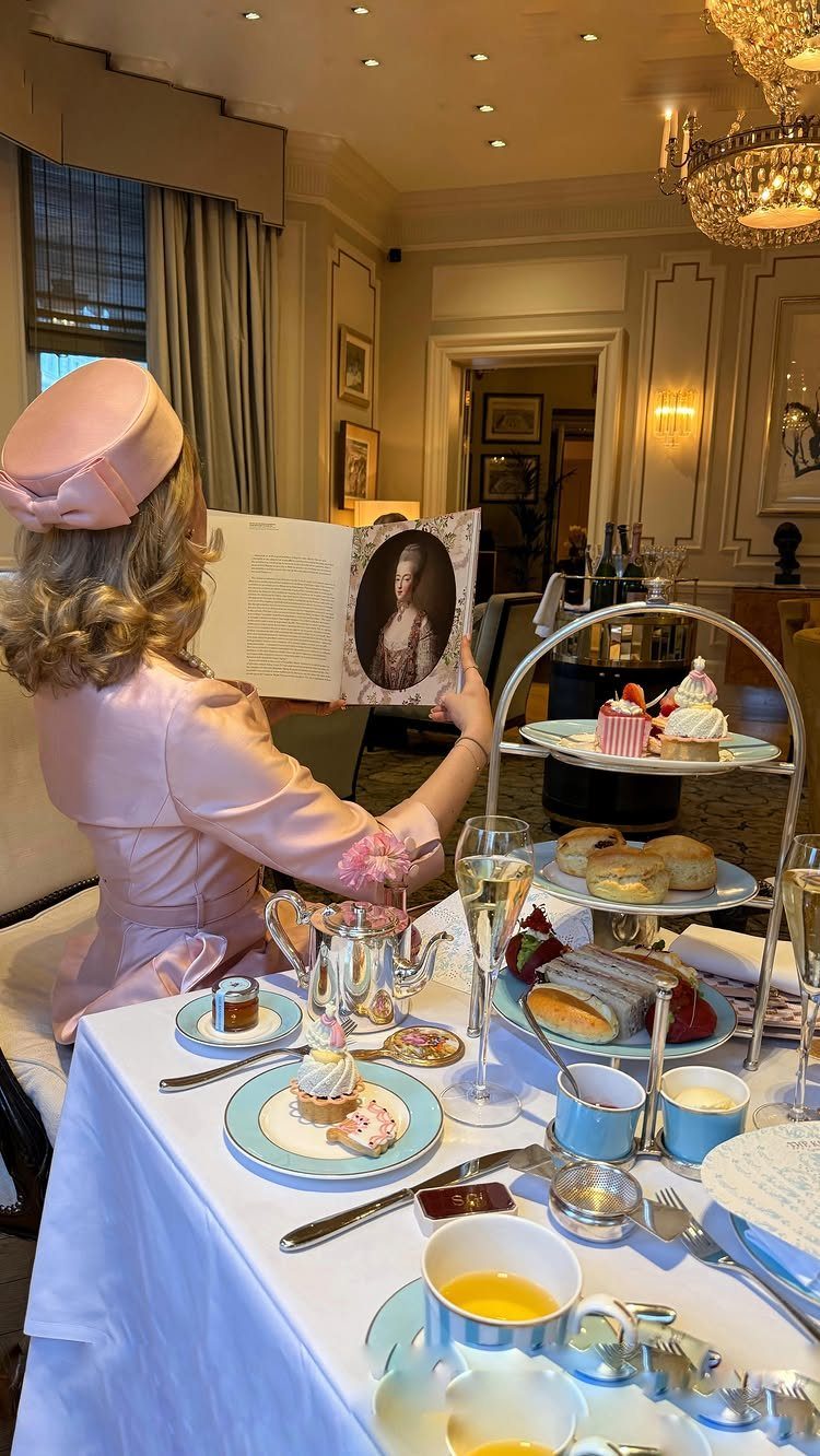 Woman in pink formal attire sitting at a table prepared for an elegant afternoon tea service.