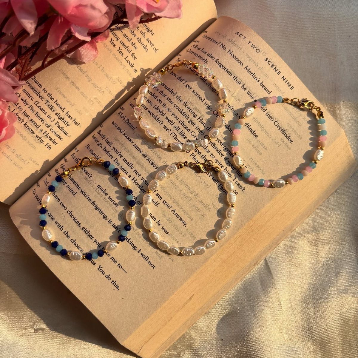 Three beaded pearl bracelets resting on the pages of an open book with pink flowers.