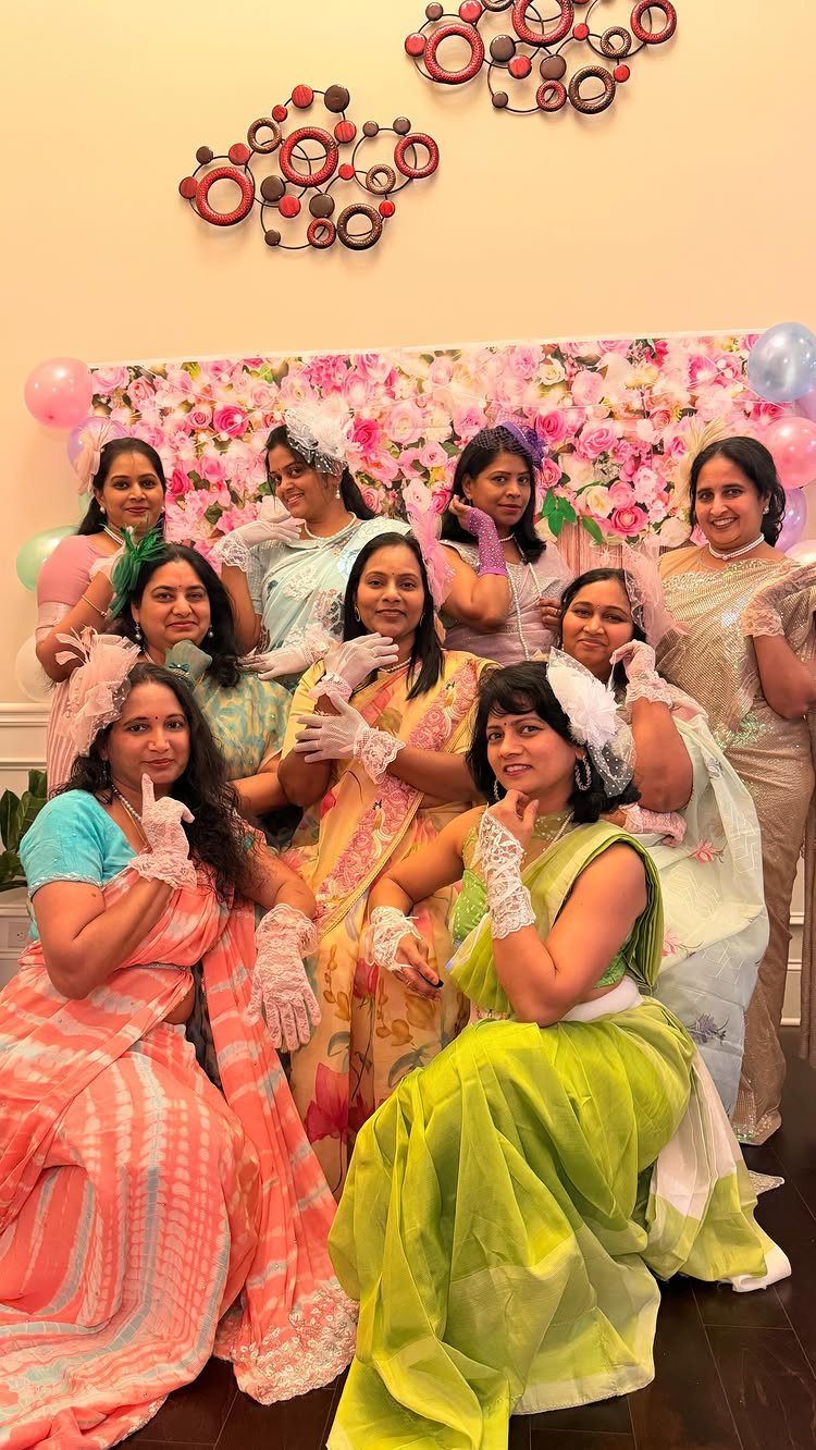 Group of women in colorful sarees posing together while wearing white lace gloves.