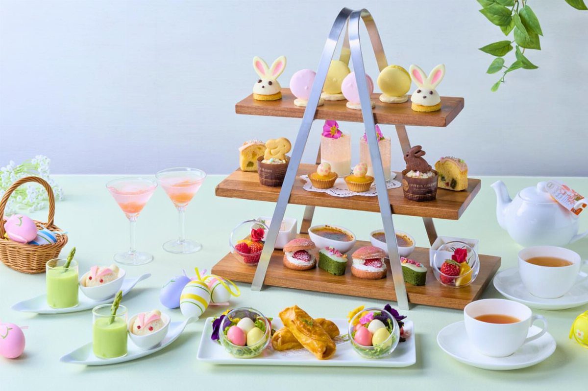 A tiered wooden stand filled with bunny-shaped desserts and colorful treats for an Easter tea party.