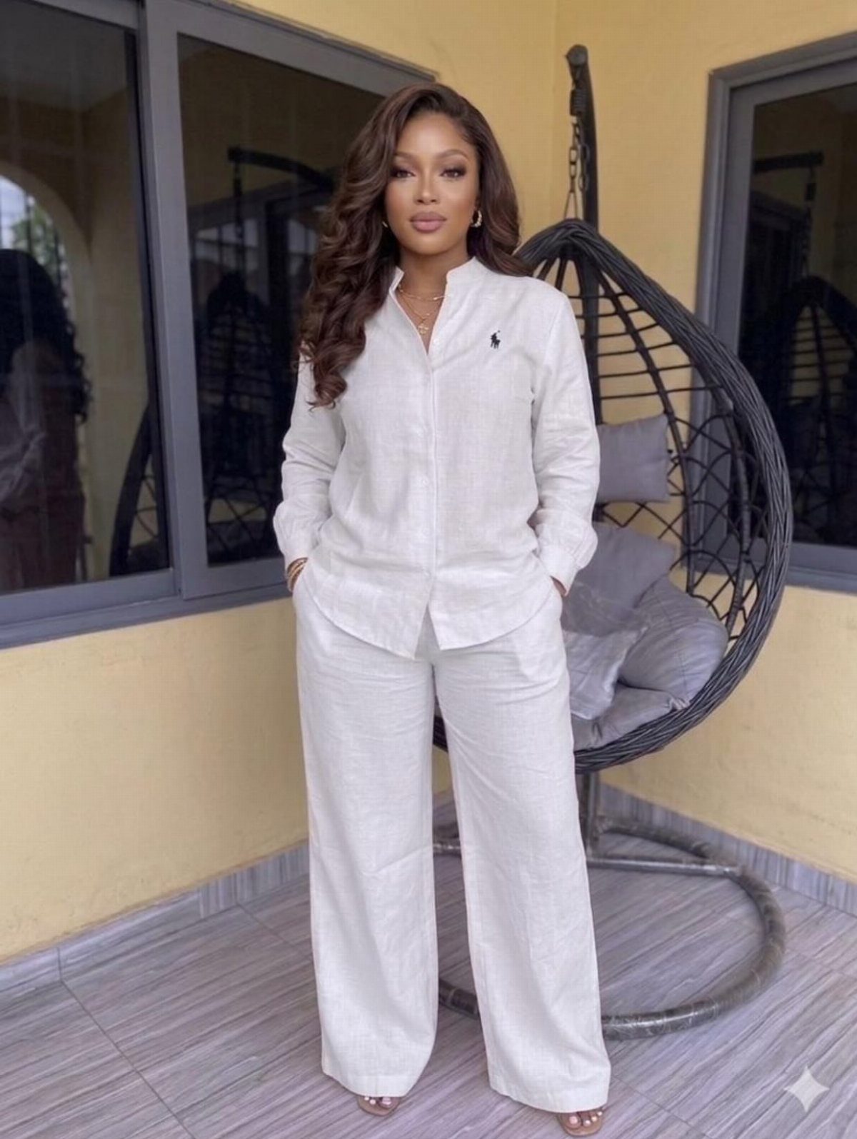 Woman posing in a white linen two-piece shirt and wide-leg trousers outfit.