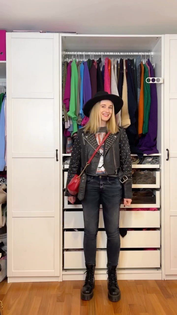 A woman wearing a black leather jacket, grey t-shirt, dark jeans, and black boots.
