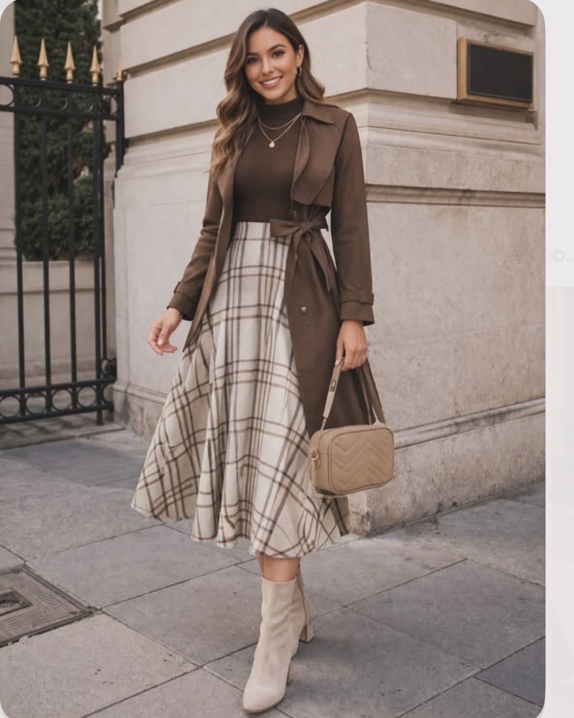 A woman wearing a brown turtleneck, plaid midi skirt, and brown trench coat walking outdoors.