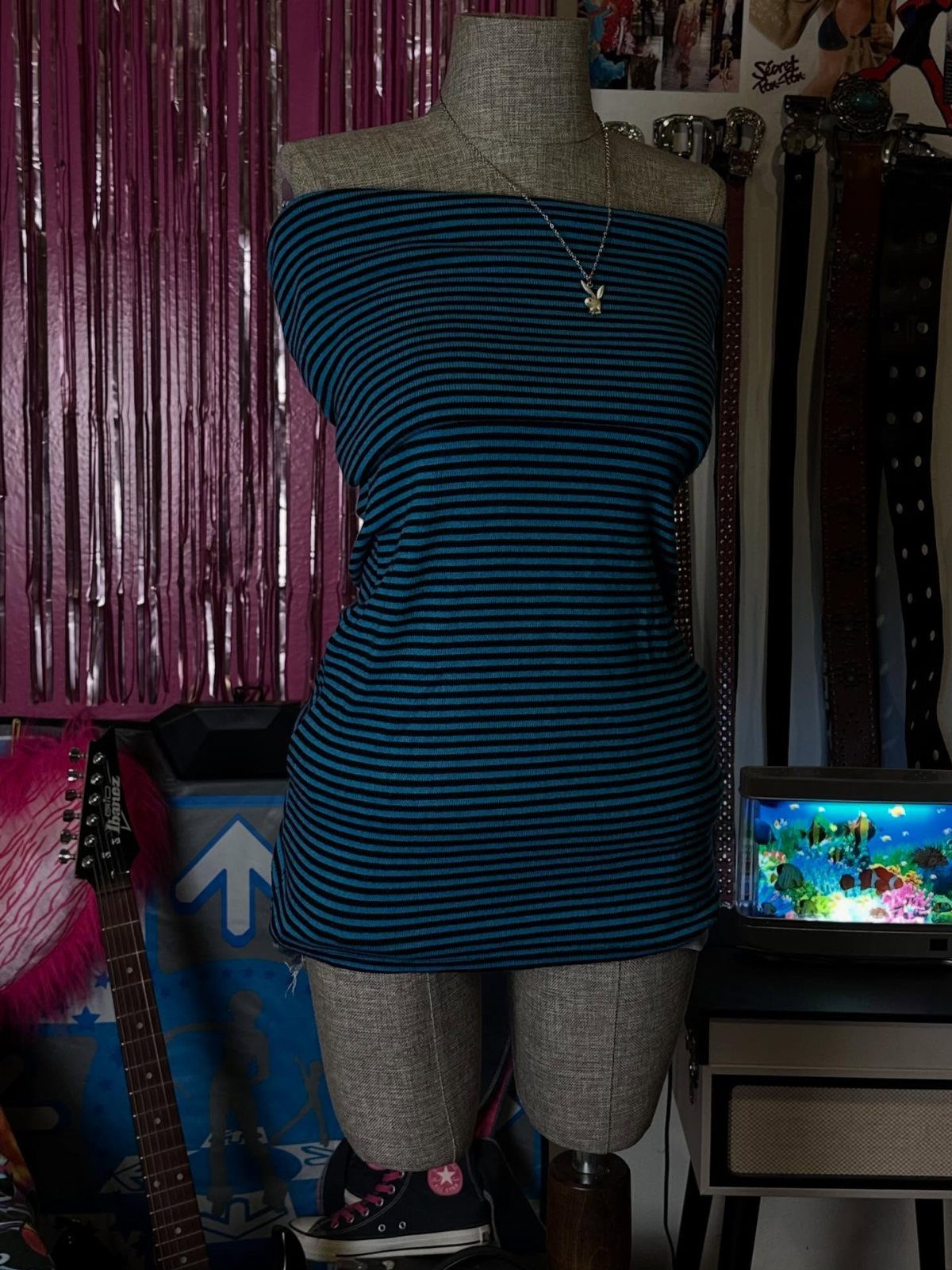 A mannequin wearing a blue and black striped strapless mini dress with a silver necklace.