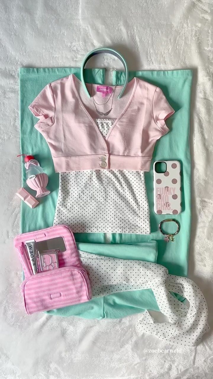 Pink cropped cardigan and polka dot top laid out with mint green pants and accessories.