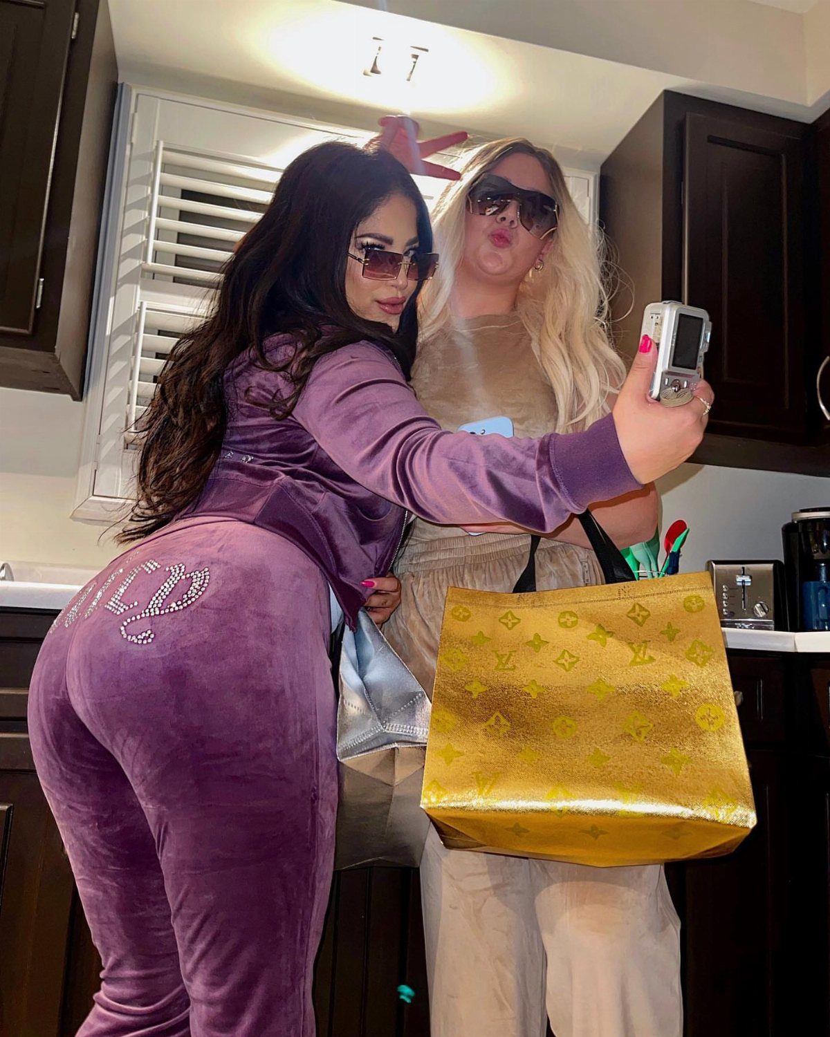 Two women posing for a selfie, one wearing a purple velour tracksuit.