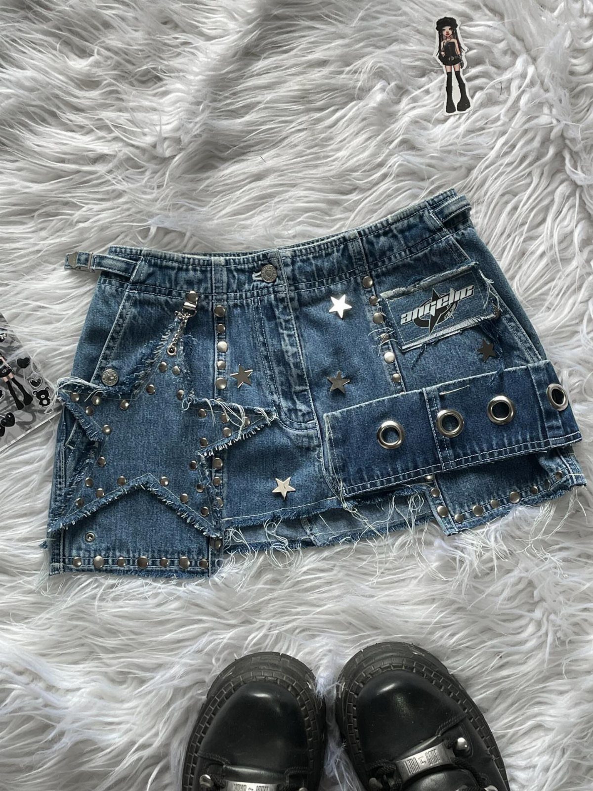 Blue denim mini skirt with star embellishments and metal grommets on white faux fur.